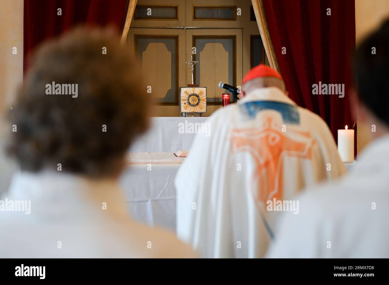 A cardinal praying in front of the altar and tabernacle after Holy Mass in a chapel. Stock Photo