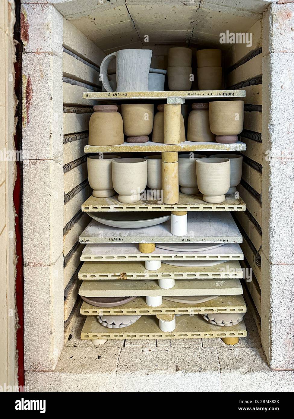 Bone dry ceramic pieces packed in a kiln to be bisque fired Stock Photo