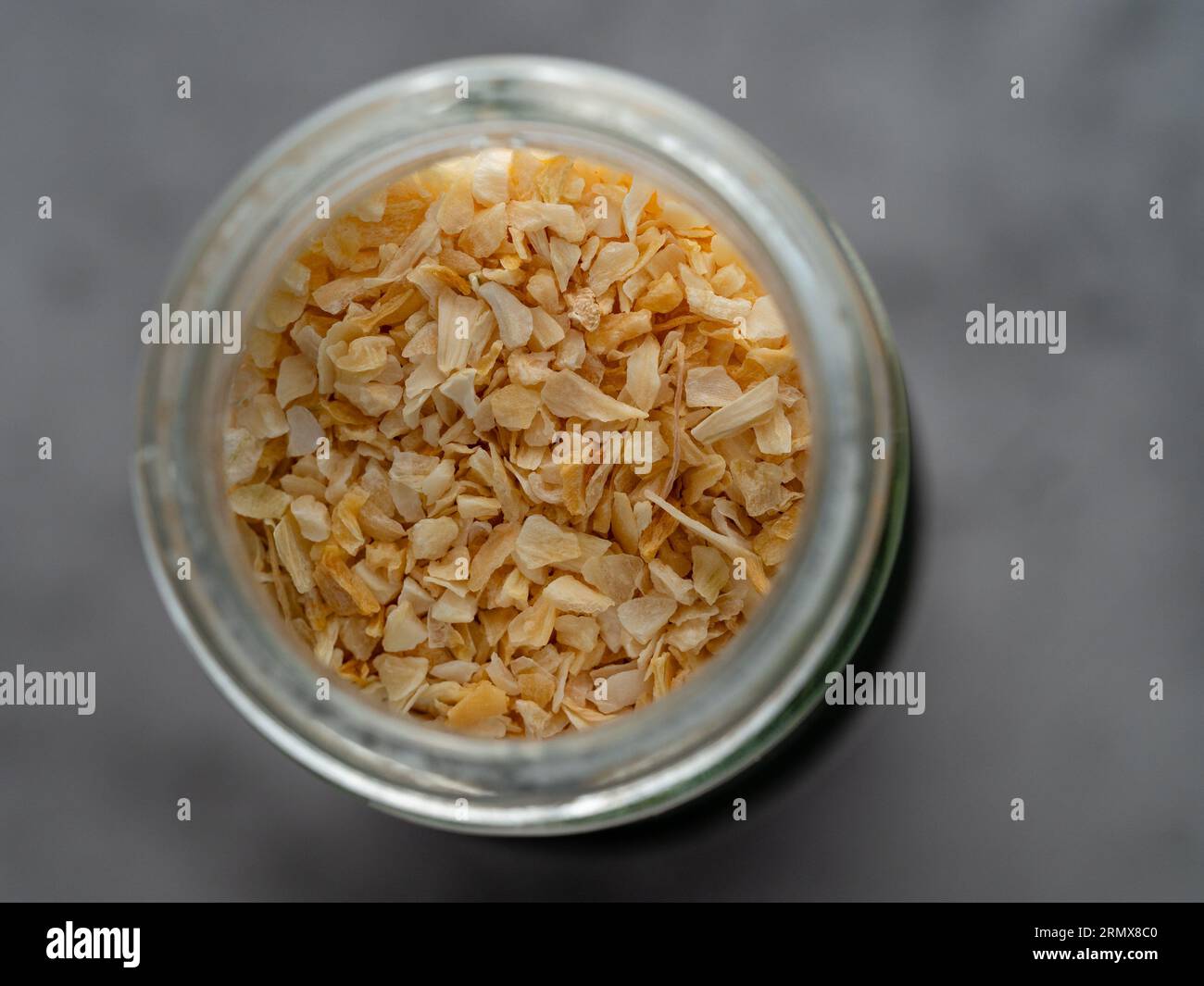Dried aromatic garlic granules in a glass jar closeup Stock Photo