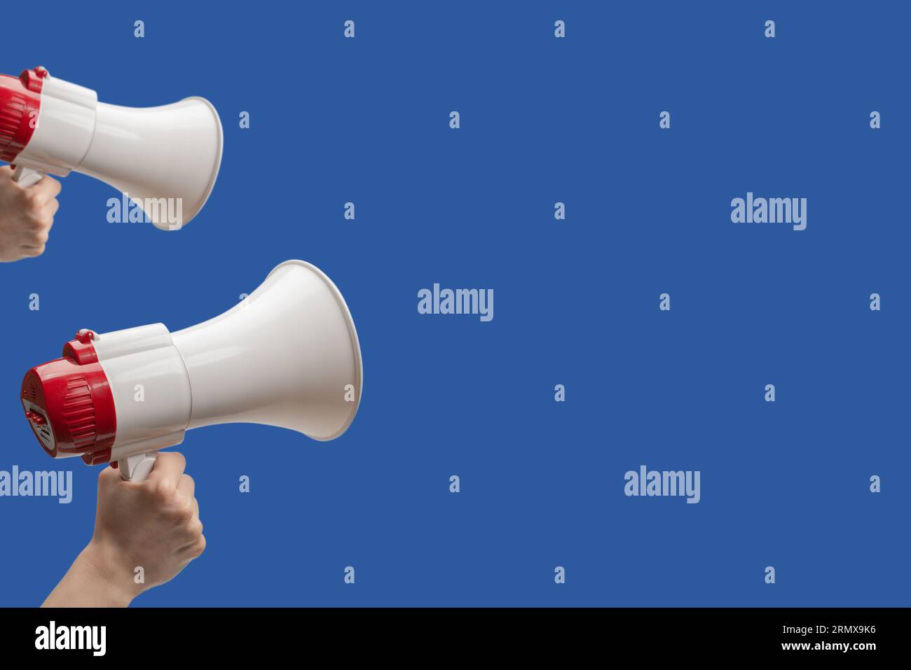 Megaphone in woman hands on a blue background.  Copy space. Stock Photo