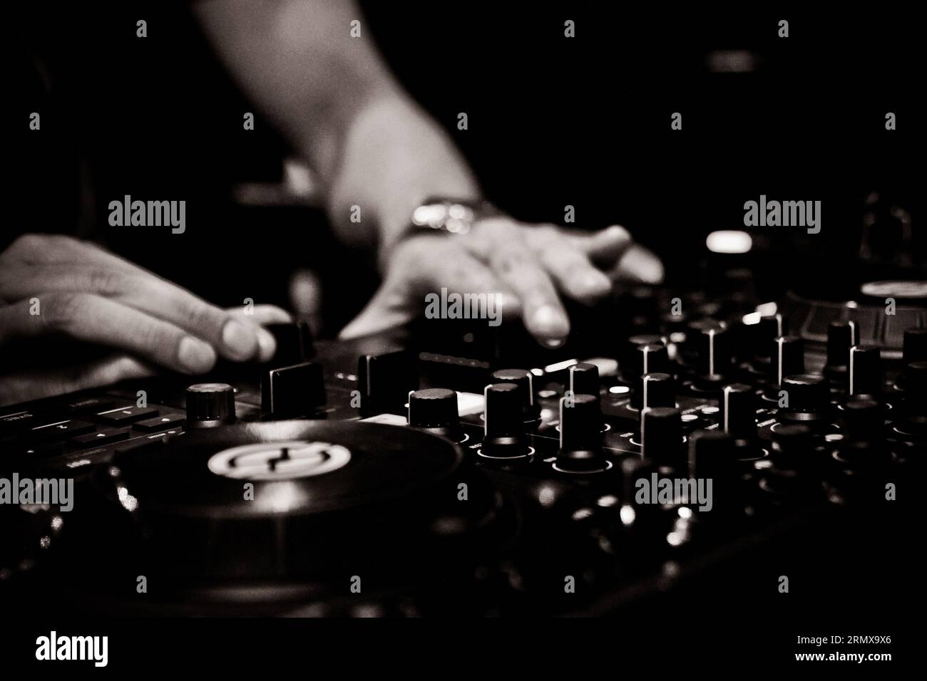Club DJ adjusting controls on mixer. Stock Photo