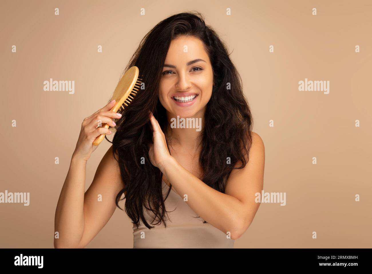 Cheerful indian woman combing beautiful dark long hair, studio background Stock Photo