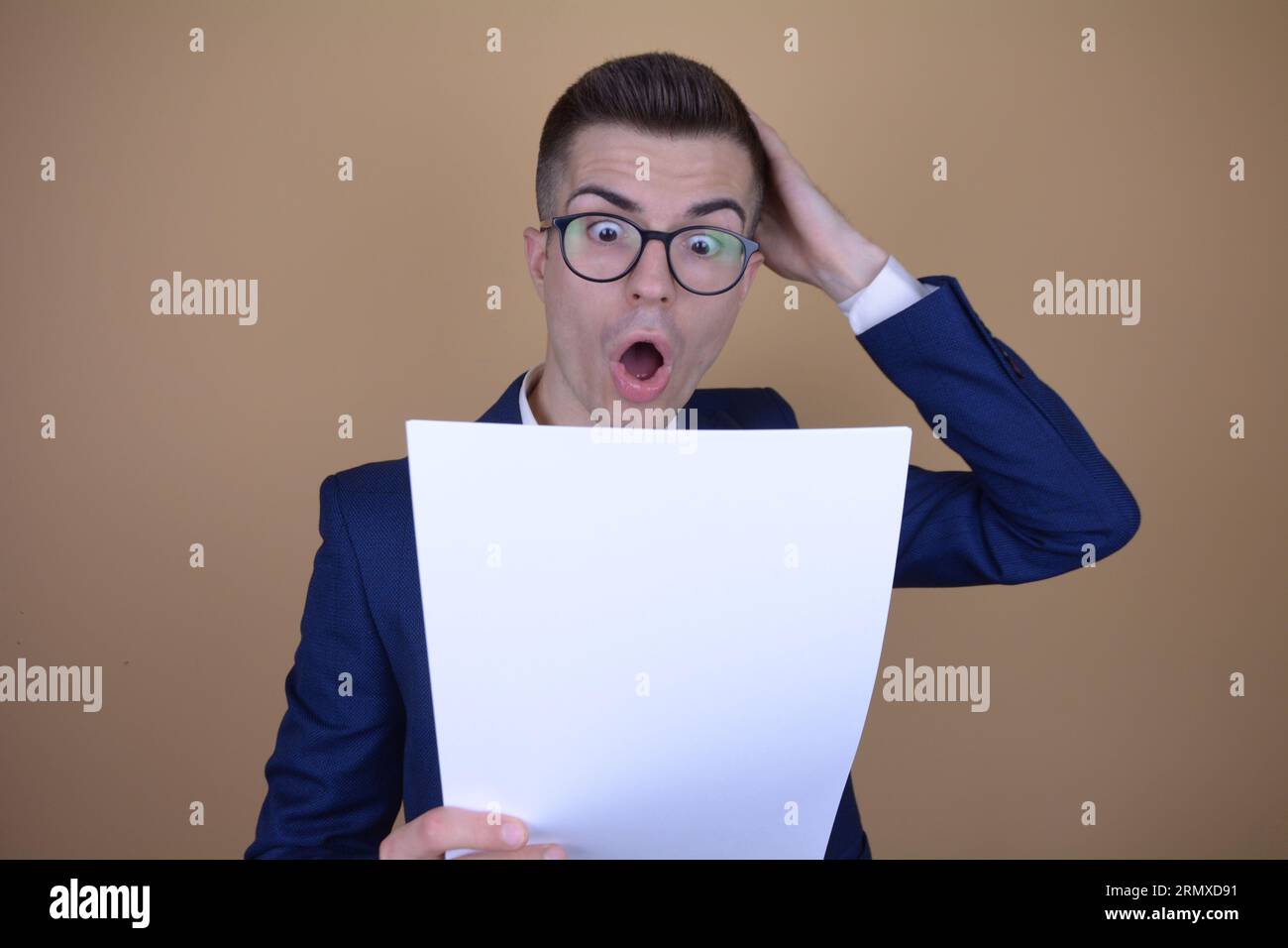 Shocked Young Handsome Elegant Man Holding His Head While Reading Documents on Isolated Background Stock Photo