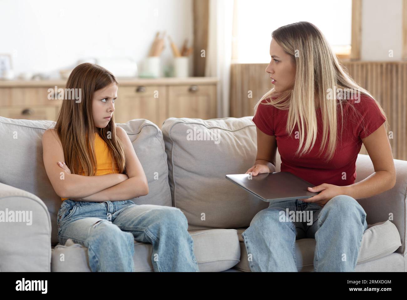 Strict mother scolding preteen daughter for long laptop use Stock Photo