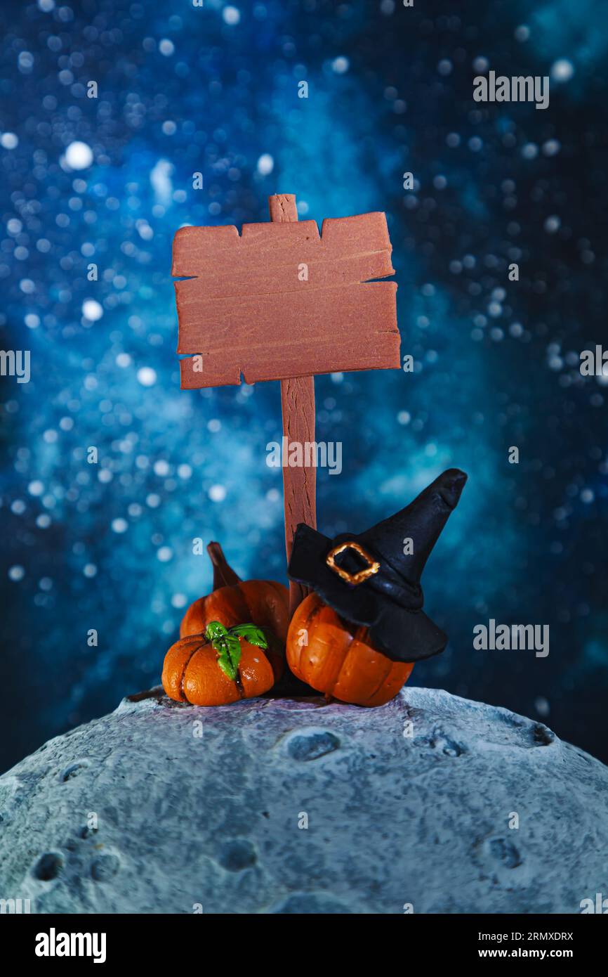 Stylized wooden signpost, witch hat and pumpkins on the moon. Mockup. Halloween background. Stock Photo
