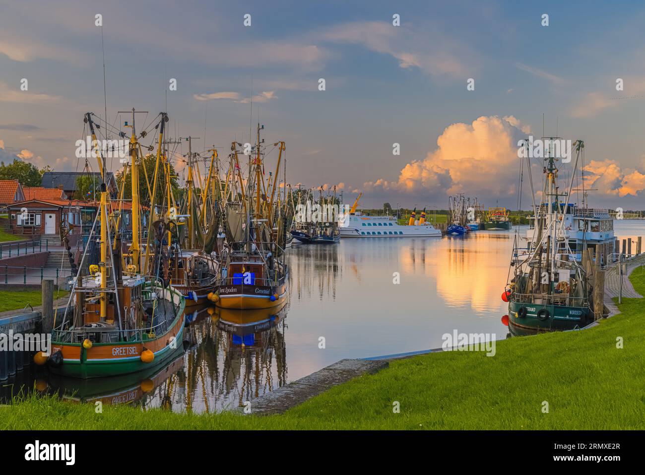 An evening photo of the picturesque harbor in the fishing village of Greetsiel. Greetsiel is a small harbor town on the Leybocht in the west of East F Stock Photo