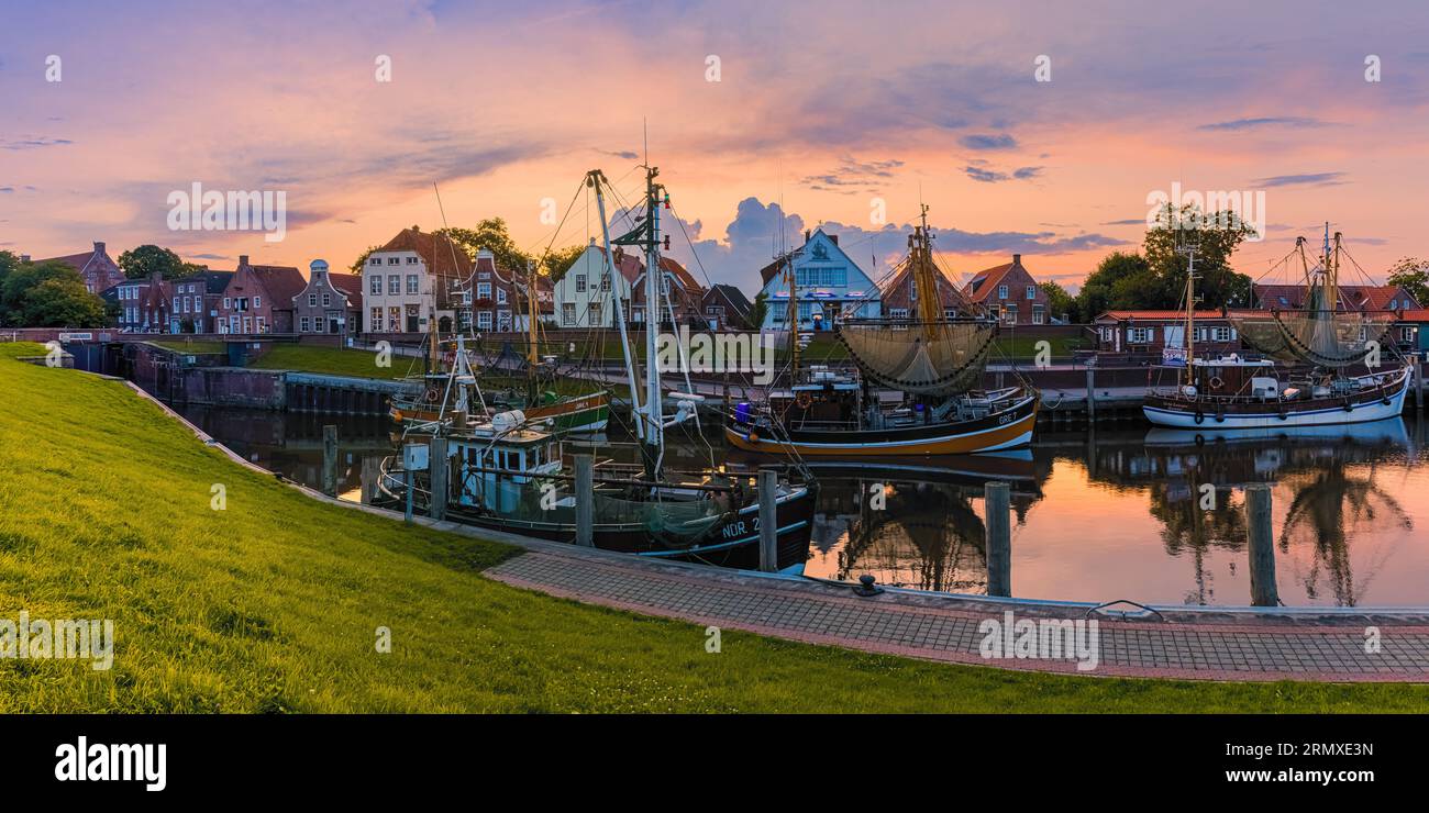 A 2:1 panorama photo of the picturesque harbor in the fishing village of Greetsiel after sunset. Greetsiel is a small harbor town on the Leybocht in t Stock Photo