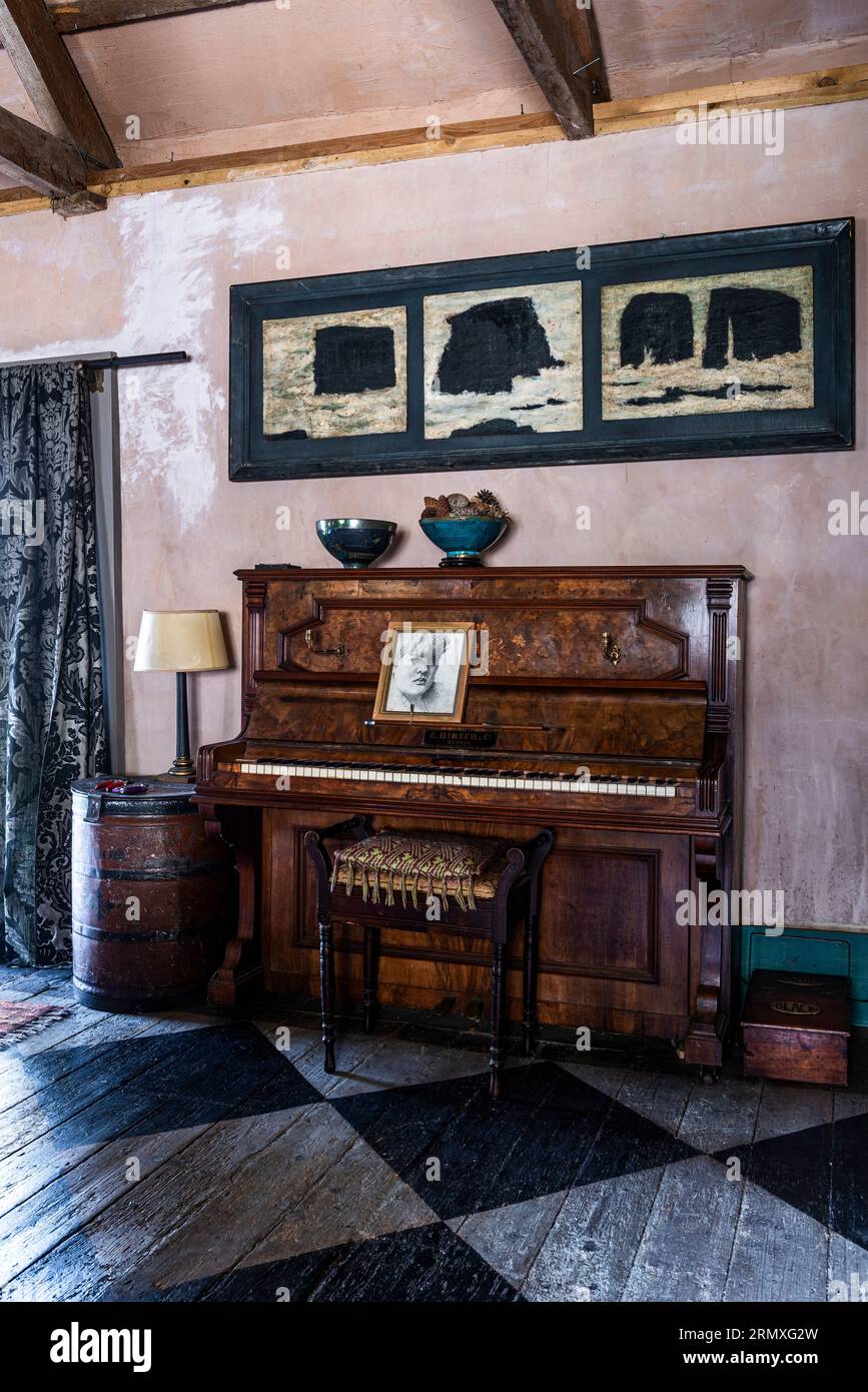 PIano with stencilled chequerboard floorboards in 18th century 'flower loft' conversion near Penzance in Cornwall, UK Stock Photo