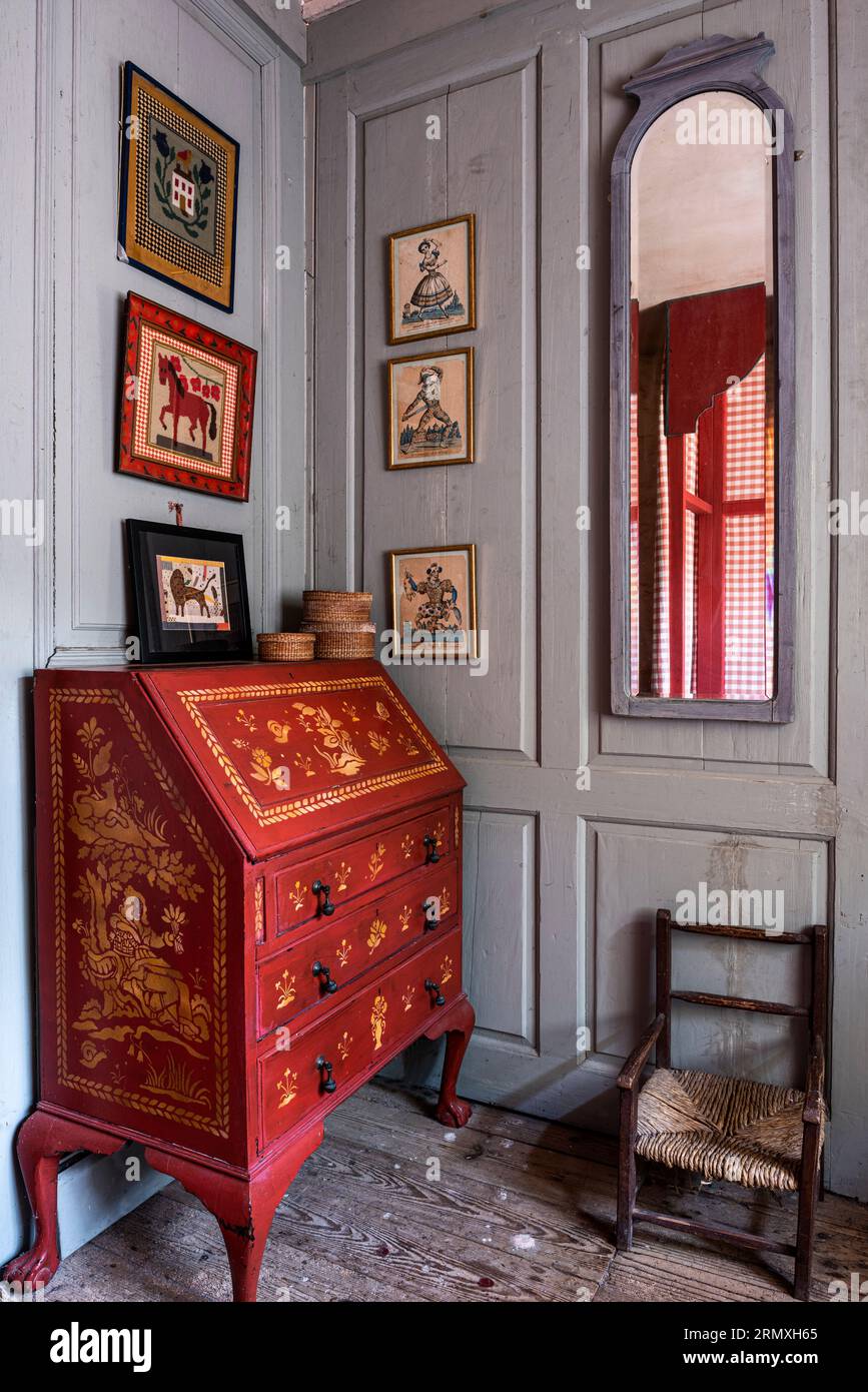 Stencilled writing desk with framed prints on panelled wall in 18th century flower loft conversion near Penzance in Cornwall, UK Stock Photo