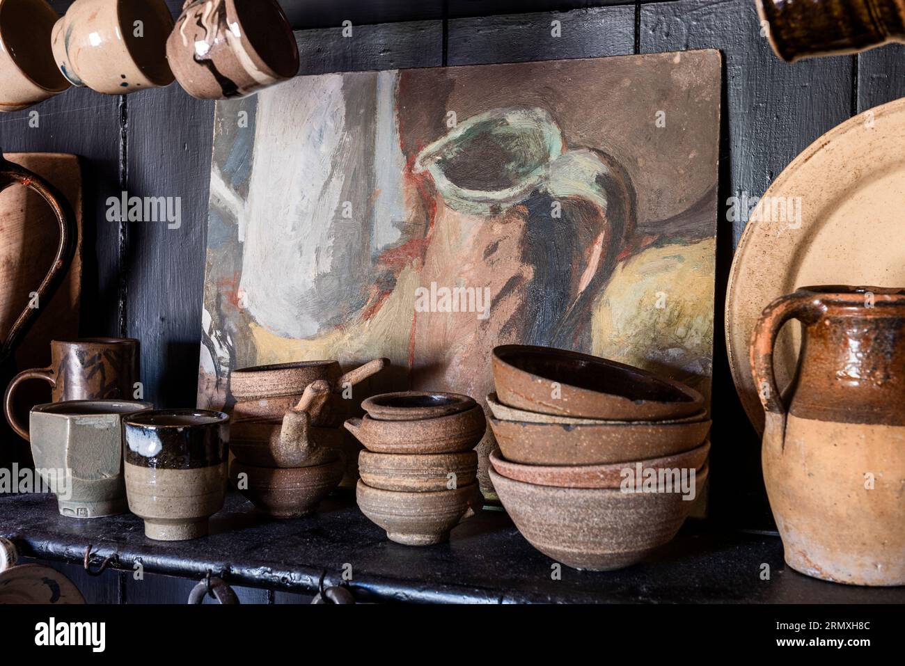 Pottery bowls and cups with artwork on dresser in 18th century flower loft conversion near Penzance in Cornwall, UK Stock Photo