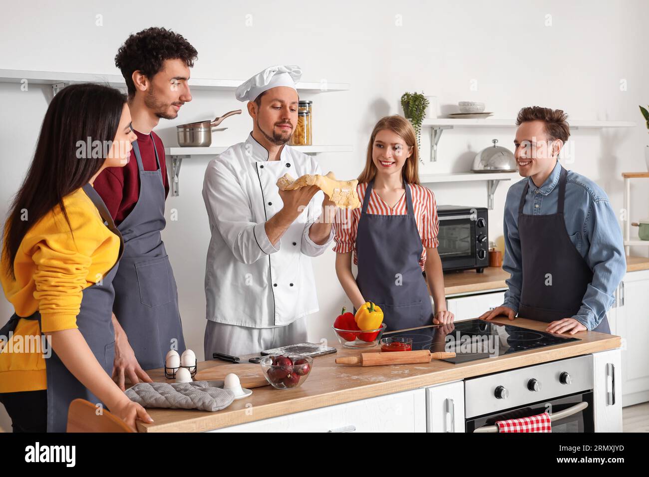 Italian chef with group of young people preparing pizza during cooking ...