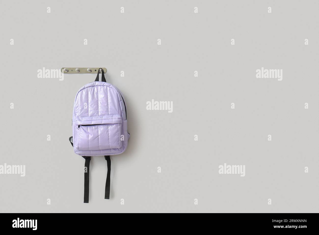 Stylish school backpack hanging on light wall Stock Photo