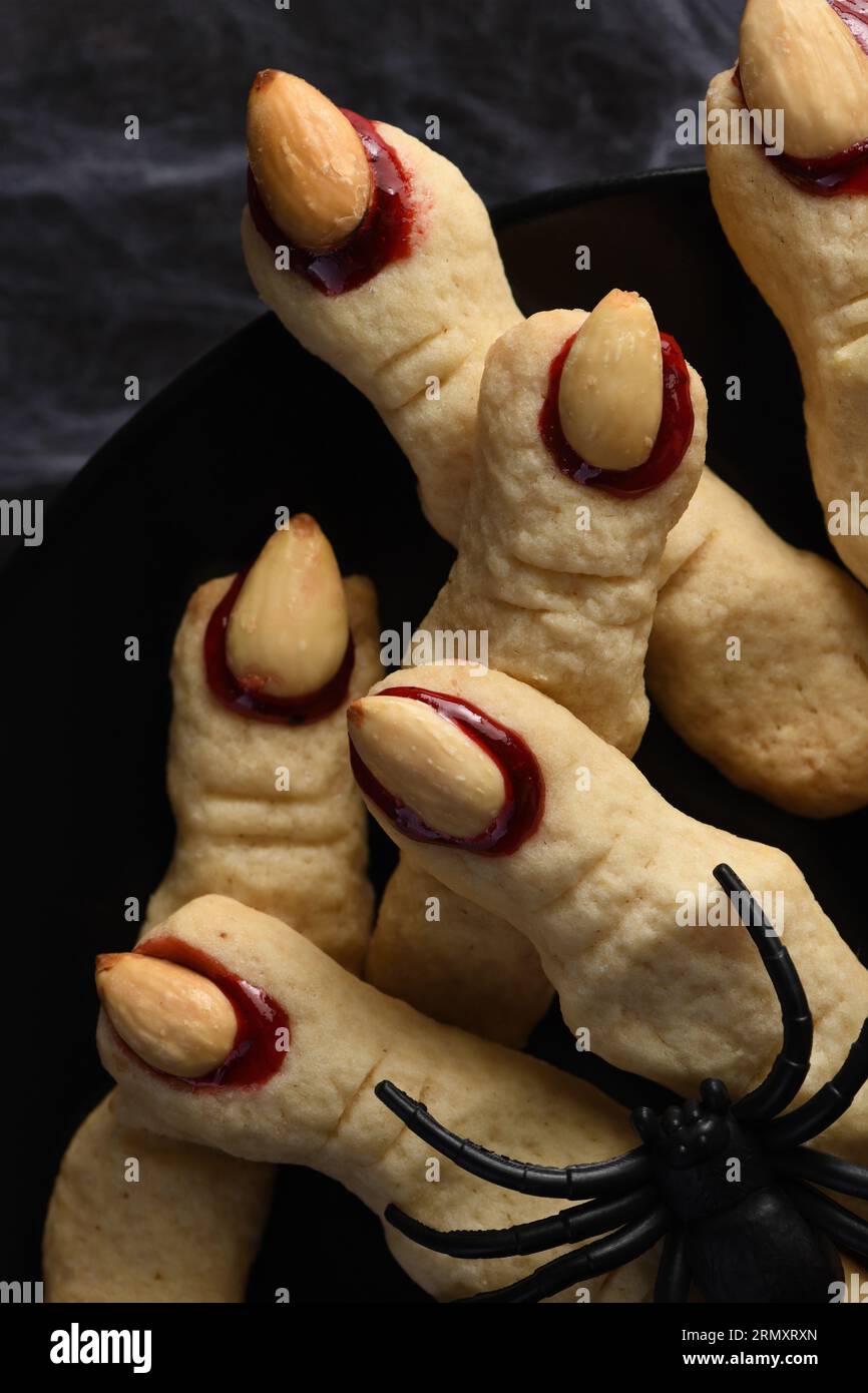 Creepy, scary Witch fingers made from sugar cookies with raspberry jam and almonds on Halloween. Trick-or-treat. Classic Cookie Witch Fingers takes on Stock Photo