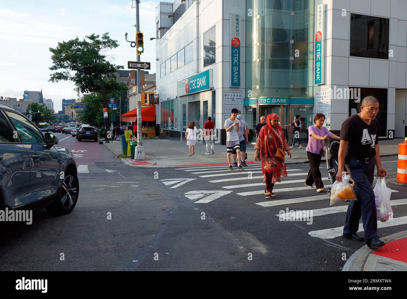 People walking across a raised crosswalk in Flushing, Queens, New York. They are speed bumps at a pedestrian crossing used for traffic calming.法拉盛, 紐約 Stock Photo