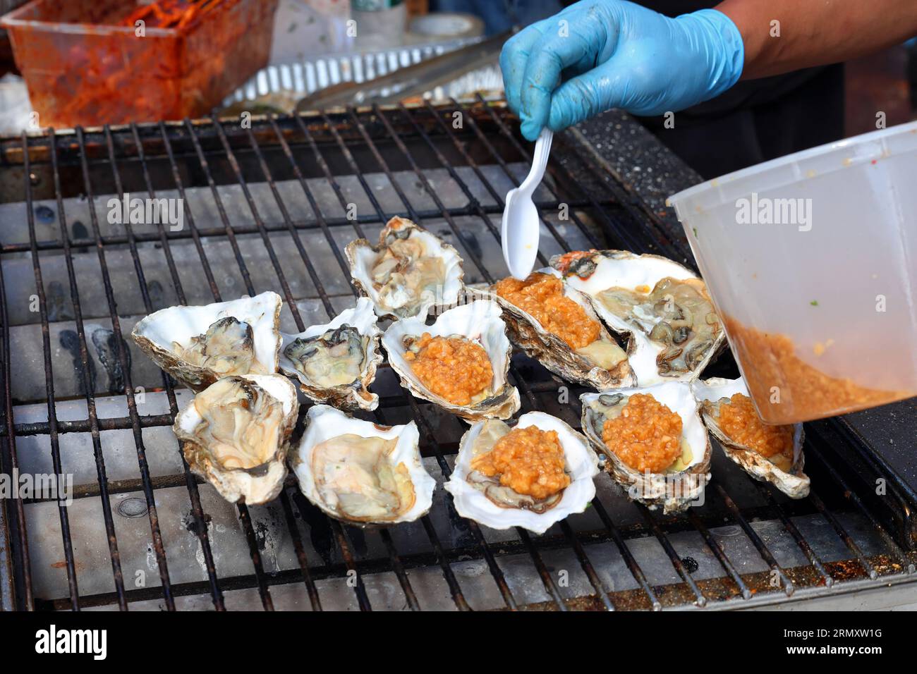 Ji Xiang BBQ cook prepares grilled oysters on the half shell at Dragon Fes food festival street fair on 4th Ave in New York City, 27 August 2023. Stock Photo