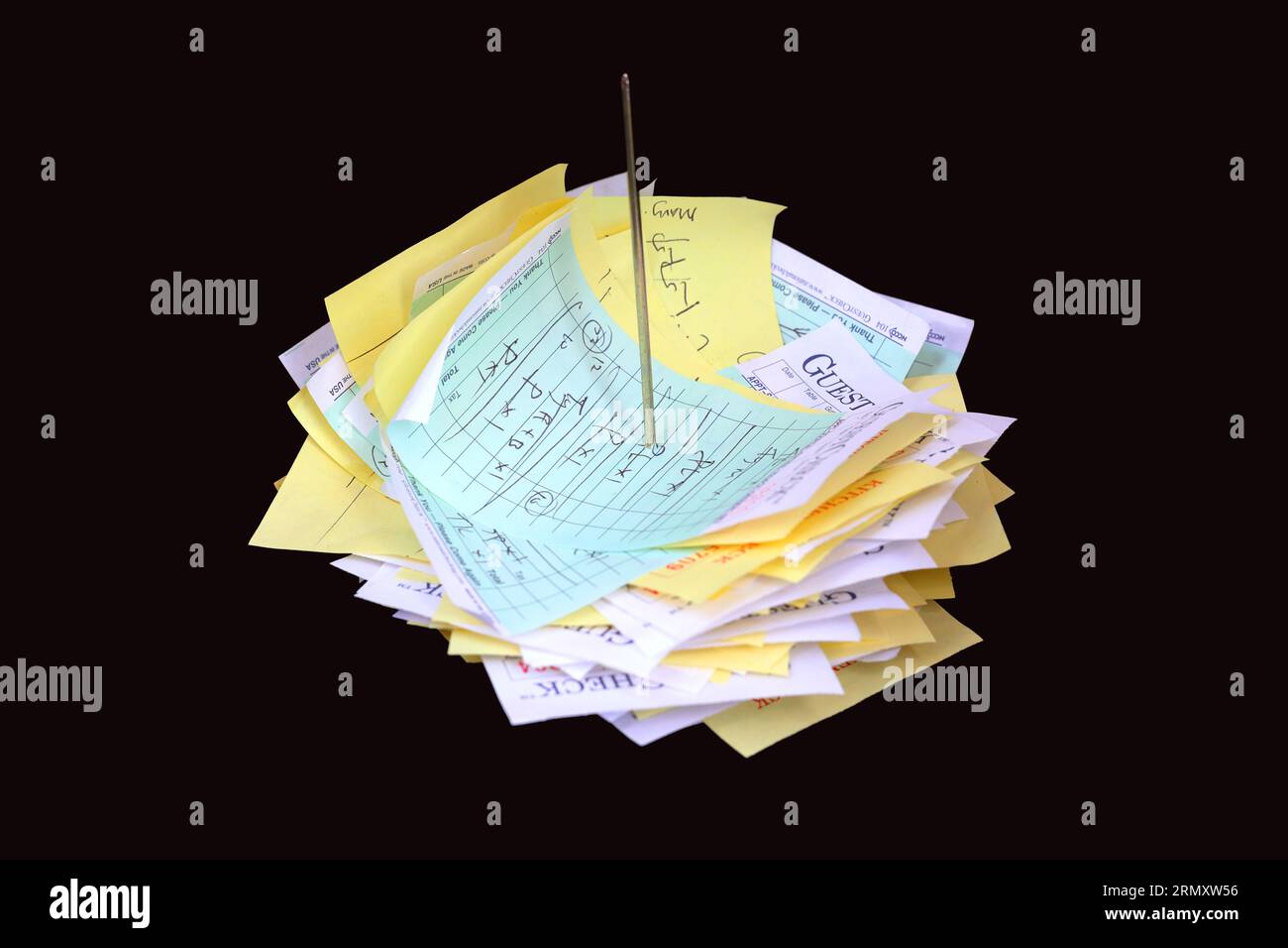 A straight rod, spiked memo holder holding food orders and receipts isolated on a black background. Stock Photo