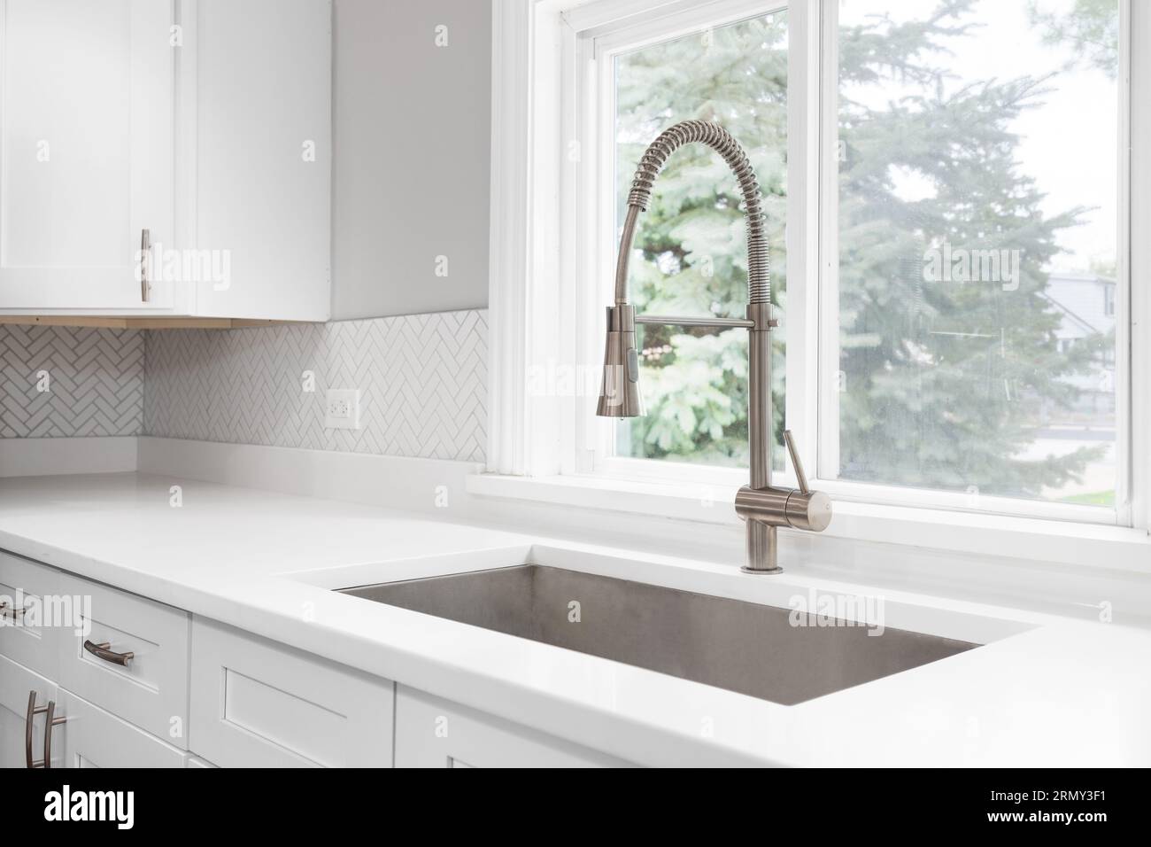 A kitchen faucet detail with a bronze faucet, white marble countertop
