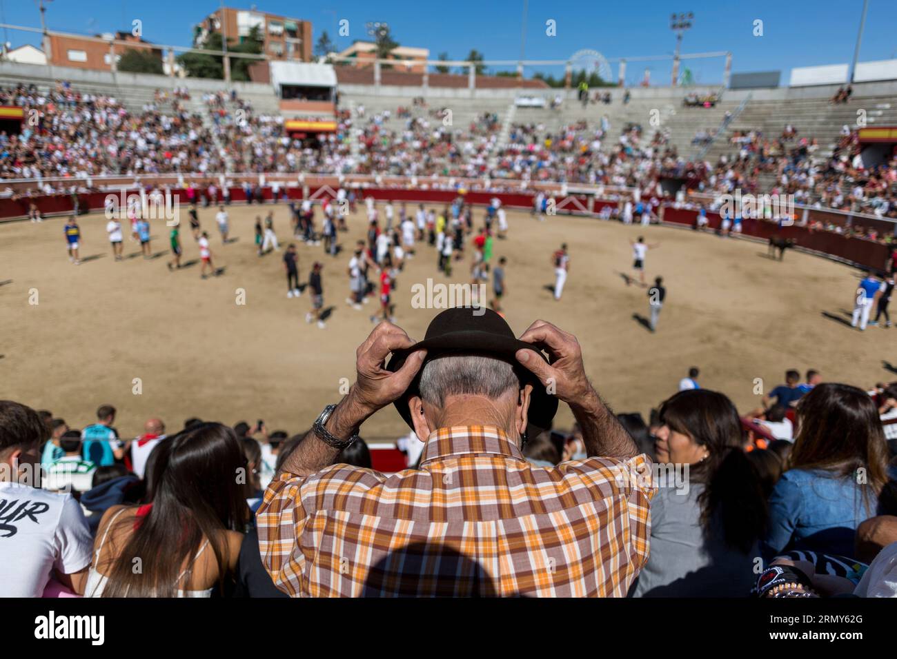 A man adjusts his hat in the stands of the bullring, during the third ...