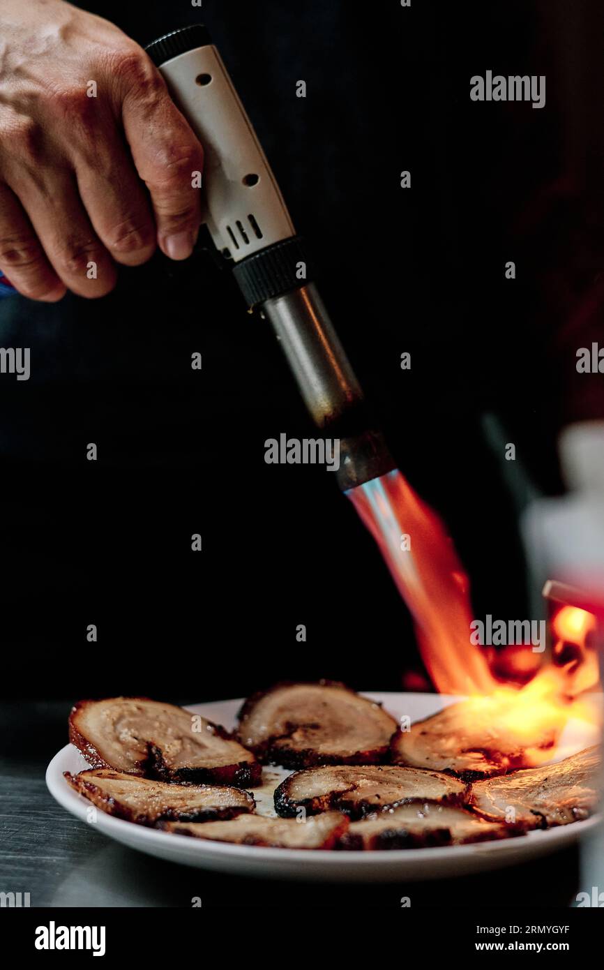 Stock photo of unrecognized chef using kitchen torch in restaurant