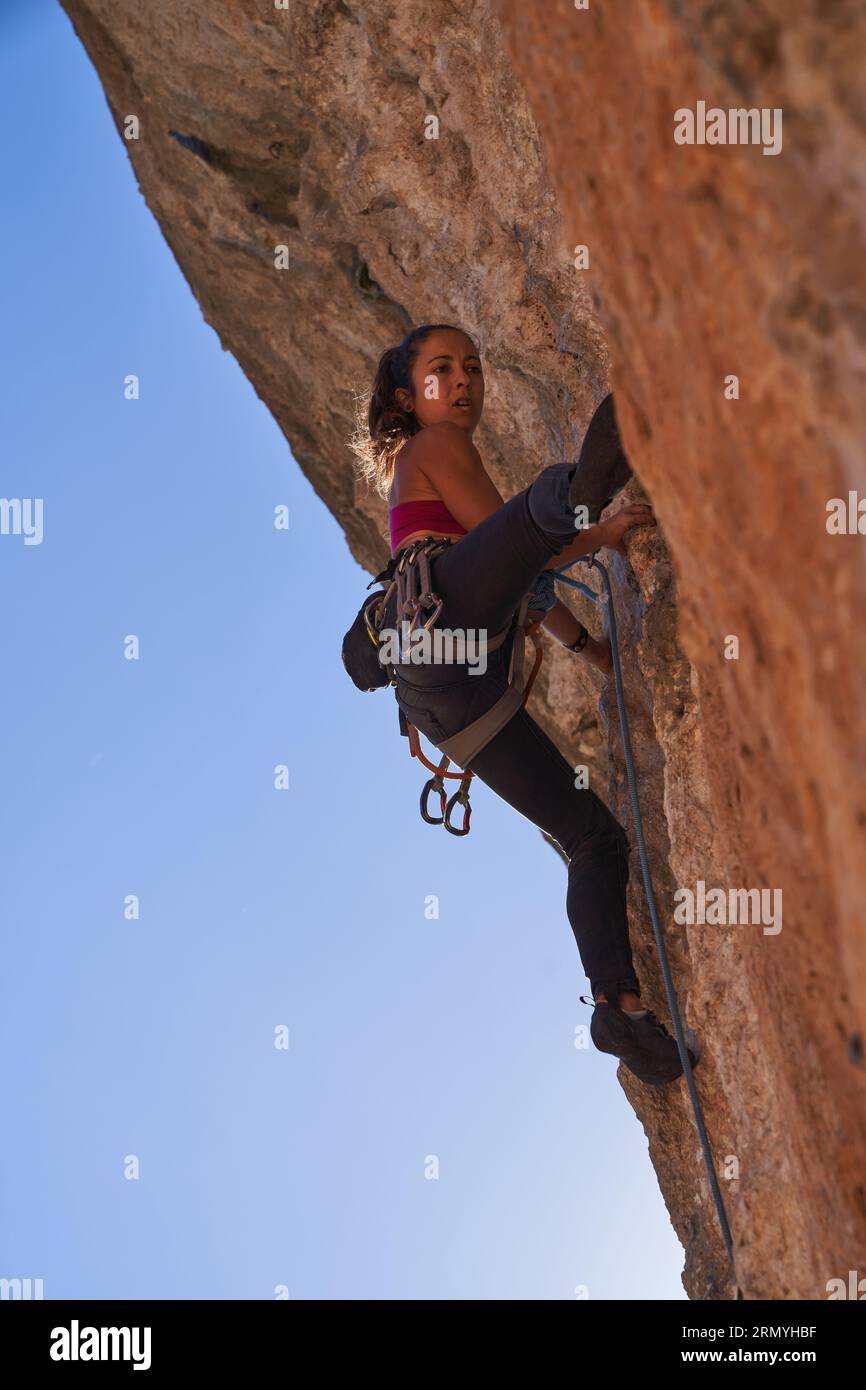 From below of female alpinist wearing safety harness sportswear and