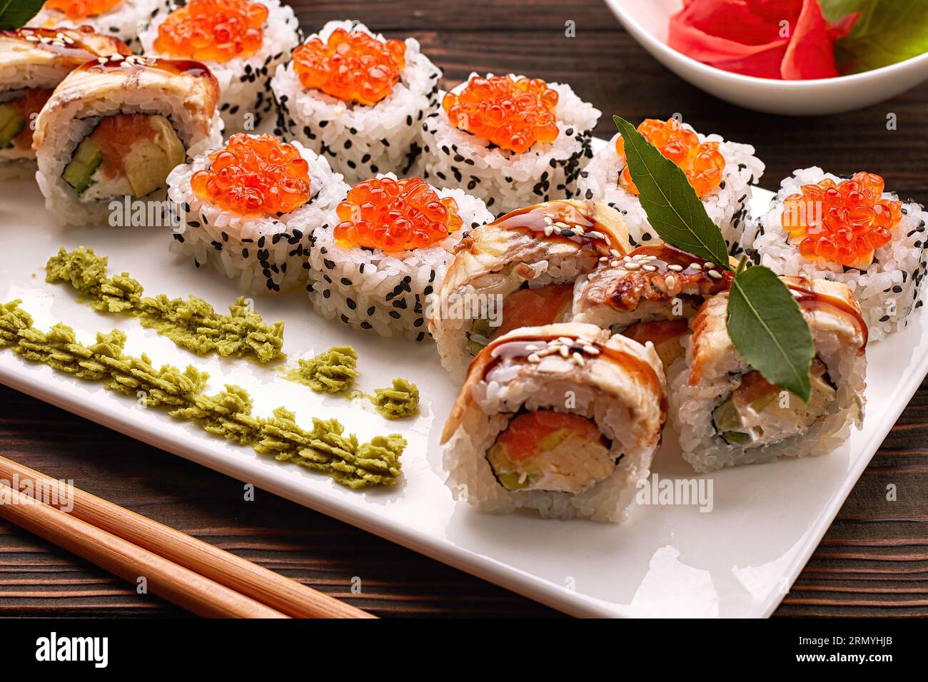 Delicious sushi rolls with wasabi and ginger with chopsticks. Close-up Stock Photo