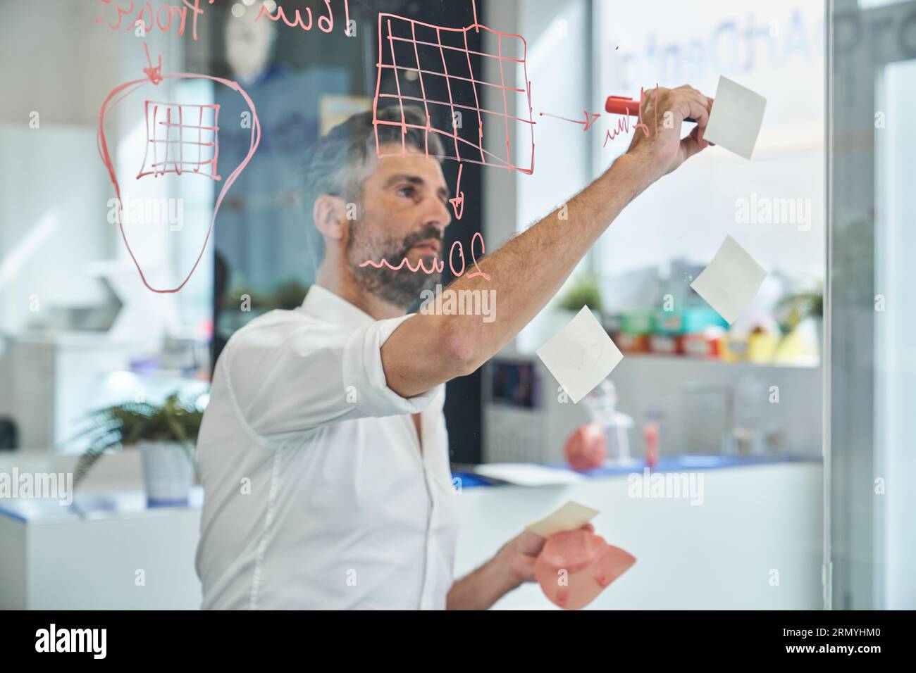 Through window of attentive male engineer in formal outfit writing on ...