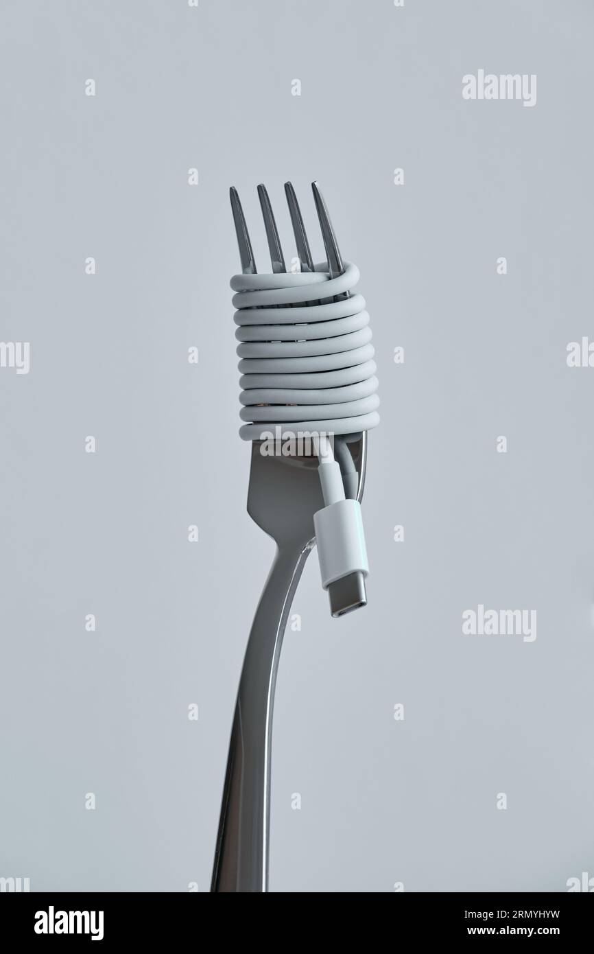 White earphones cable wrapped around steel fork like spaghetti against gray background representing data consumption concept Stock Photo