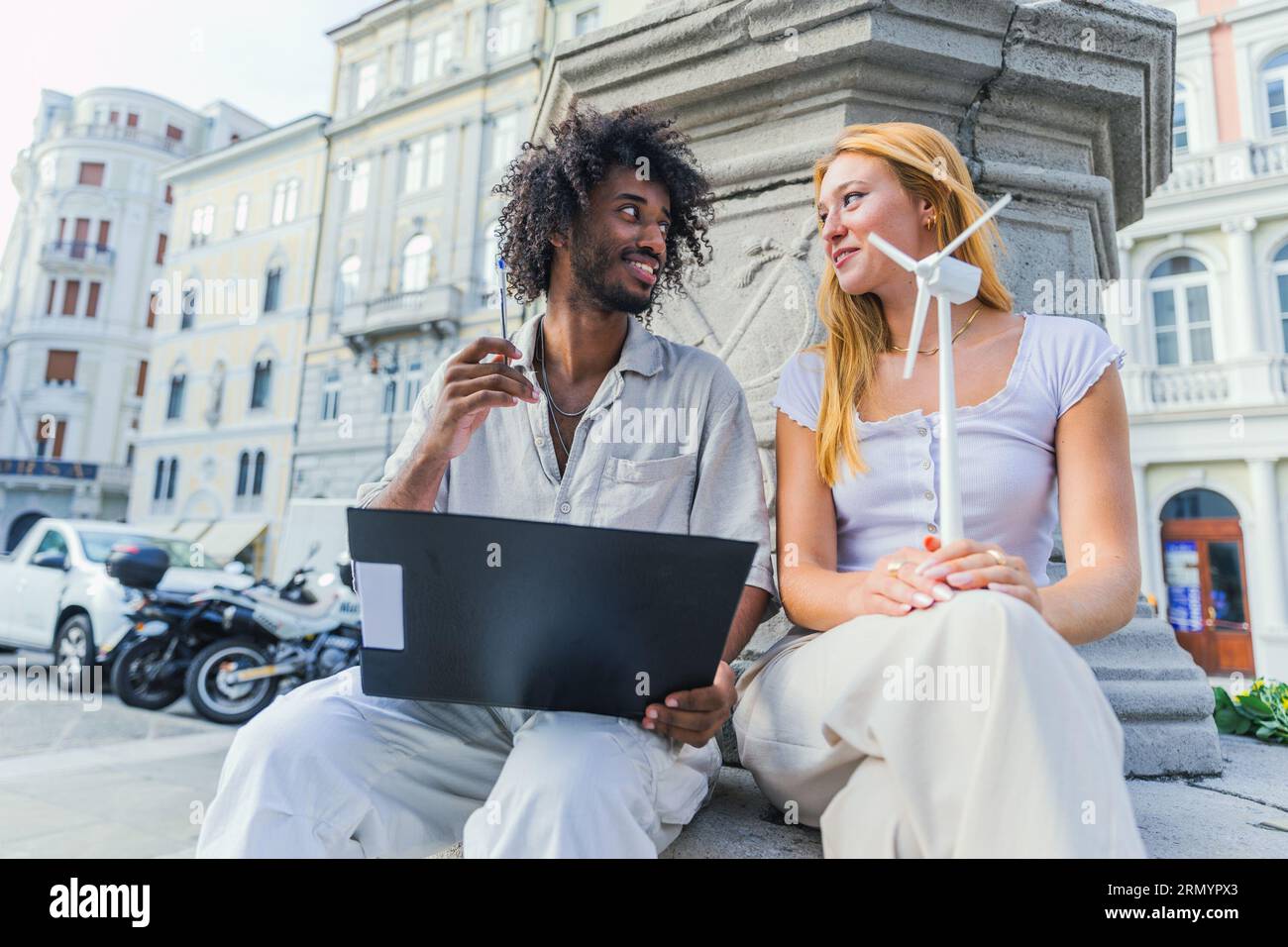 Two students study renewable energy, one reading notes the other holding a wind turbine Stock Photo