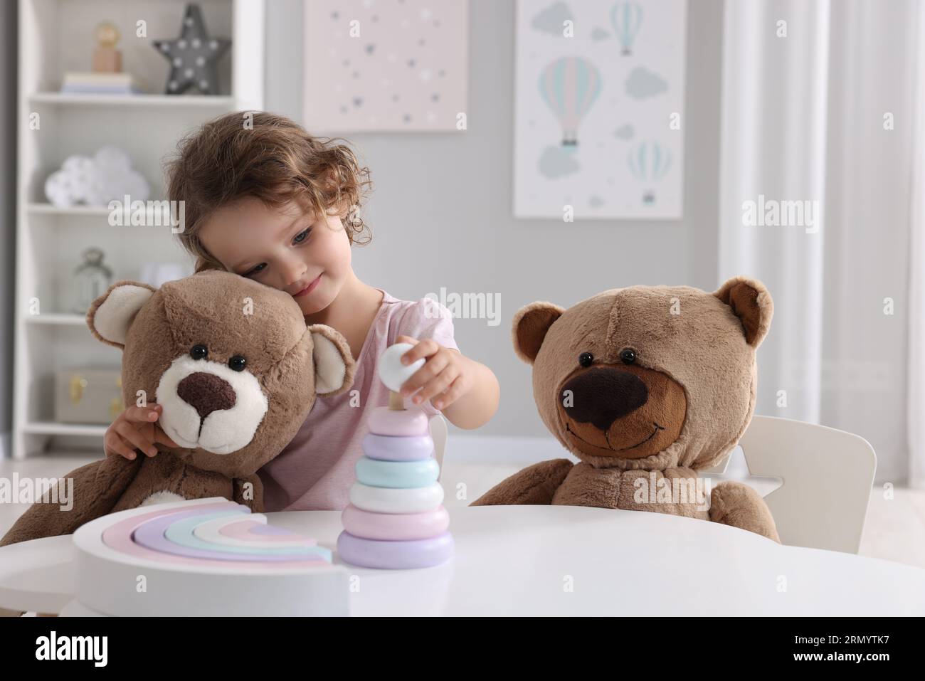 Teddy Playing Cute little girl playing with toy and teddy bears at white table in ...