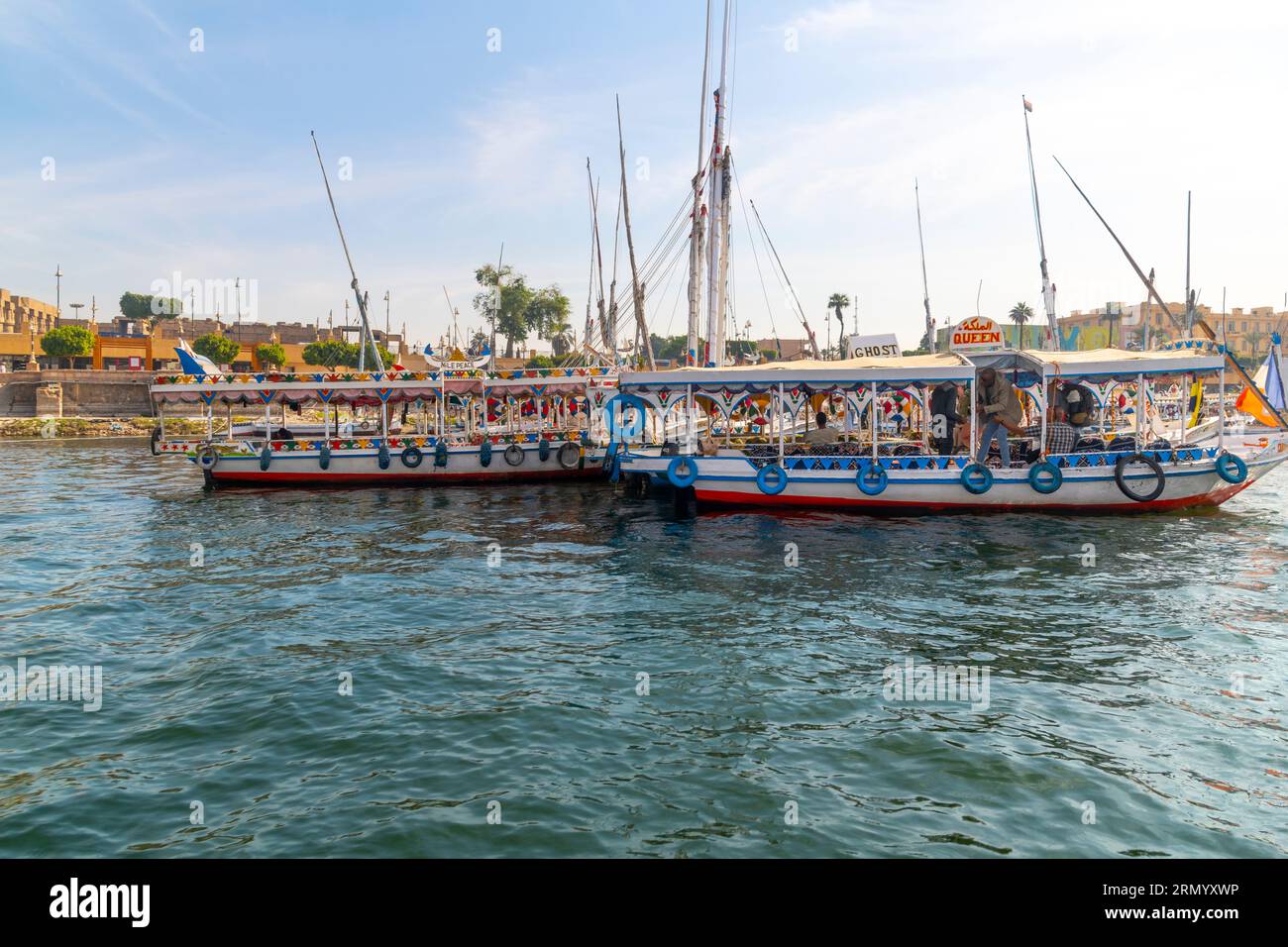 Colorful touristic river cruise boats and feluccas on the African Nile River as they travel through the central district of Luxor, Egypt. Stock Photo