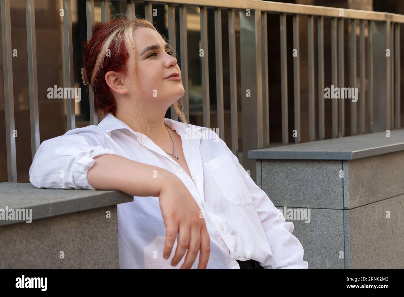 Young Real Beautiful Brown Haired Student In Jeans And T-shirt Chilling On Stone Steps, Railing Outside. Carefree Dreaming Relaxed Zoomer, Woman Stock Photo