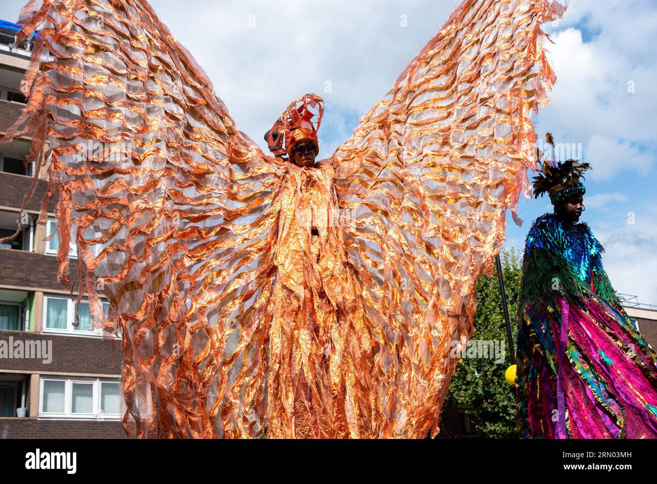 London, UK. 28th Aug, 2023. A dancer waves his costume while walking on stilts during the parade of the Notting Hill Carnival in London. The Notting Hill Carnival is one of the biggest street festivals in the world. It started in 1966 but originated with the Caribbean Carnival organised in 1959 with the immigrant community from Trinidad and Tobago. This year the Notting Hill Carnival marks the 50th anniversary of the introduction of the sound systems and Mas bands. Also it marks the 75th anniversary of the arrival of the passengers of the Empire Windrush to the UK. (Credit Image: Stock Photo