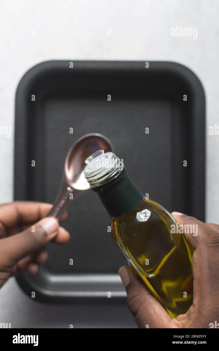 Pouring olive oil into a measuring spoon, measuring a tablespoon of oil