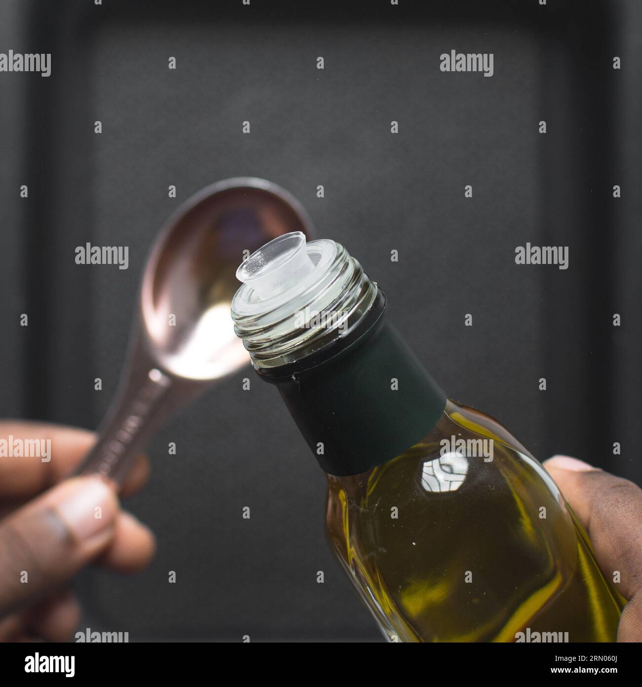 Pouring olive oil into a measuring spoon, measuring a tablespoon of oil Stock Photo Alamy
