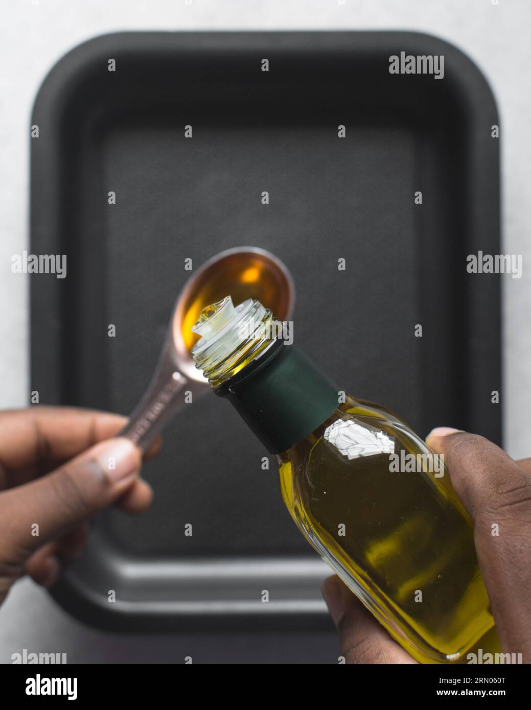 Pouring olive oil into a measuring spoon, measuring a tablespoon of oil