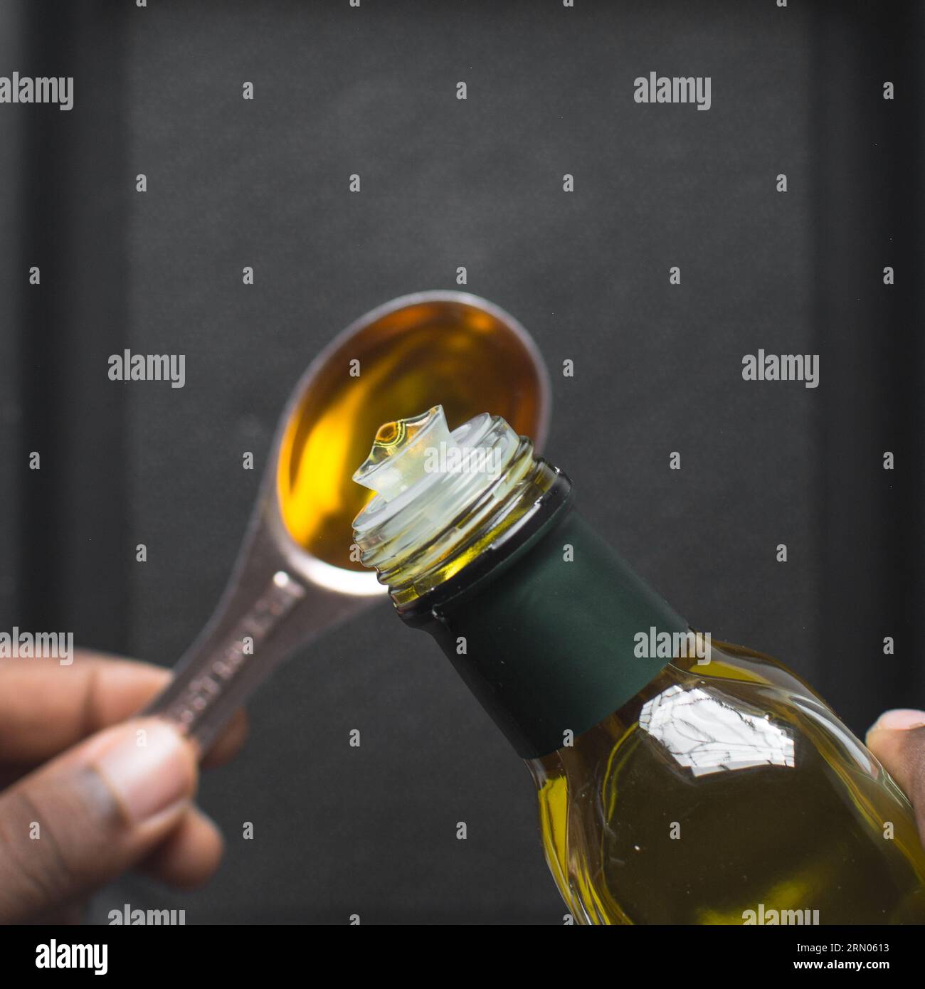 Pouring olive oil into a measuring spoon, measuring a tablespoon of oil