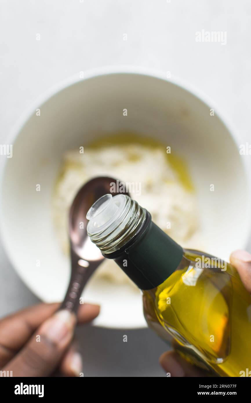 Pouring olive oil into a measuring spoon, measuring a tablespoon of oil