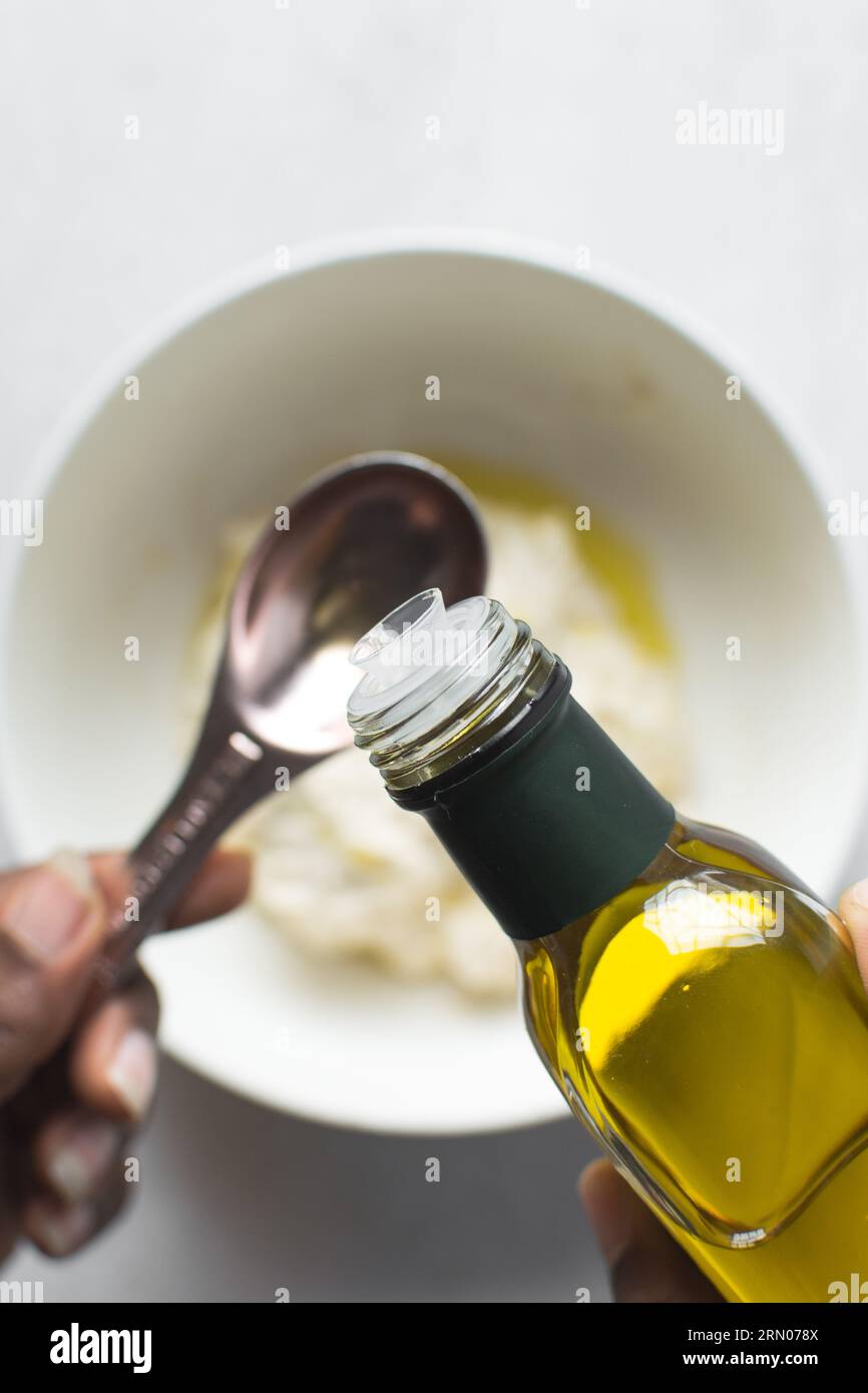 Pouring olive oil into a measuring spoon, measuring a tablespoon of oil
