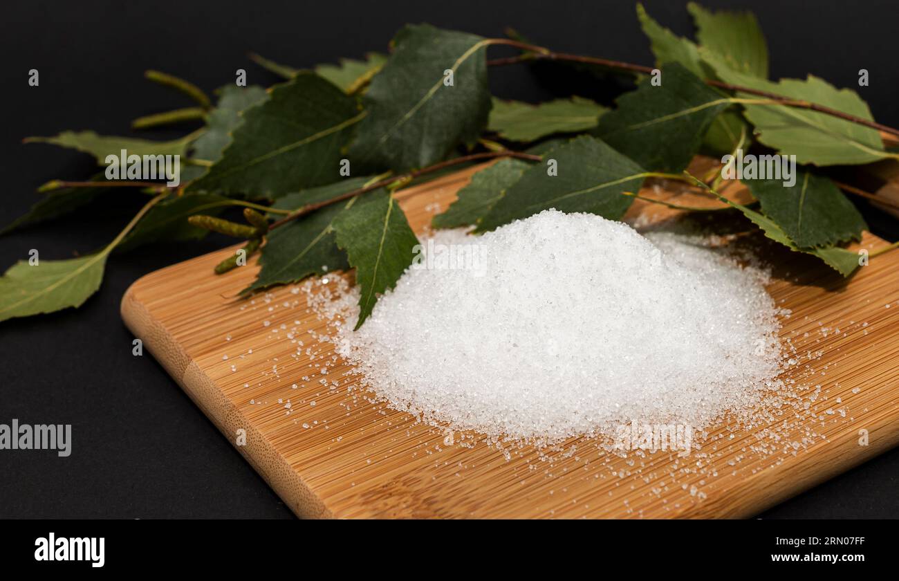 Useful sweetener Xylitol, birch sugar on cutting wooden board,sticks