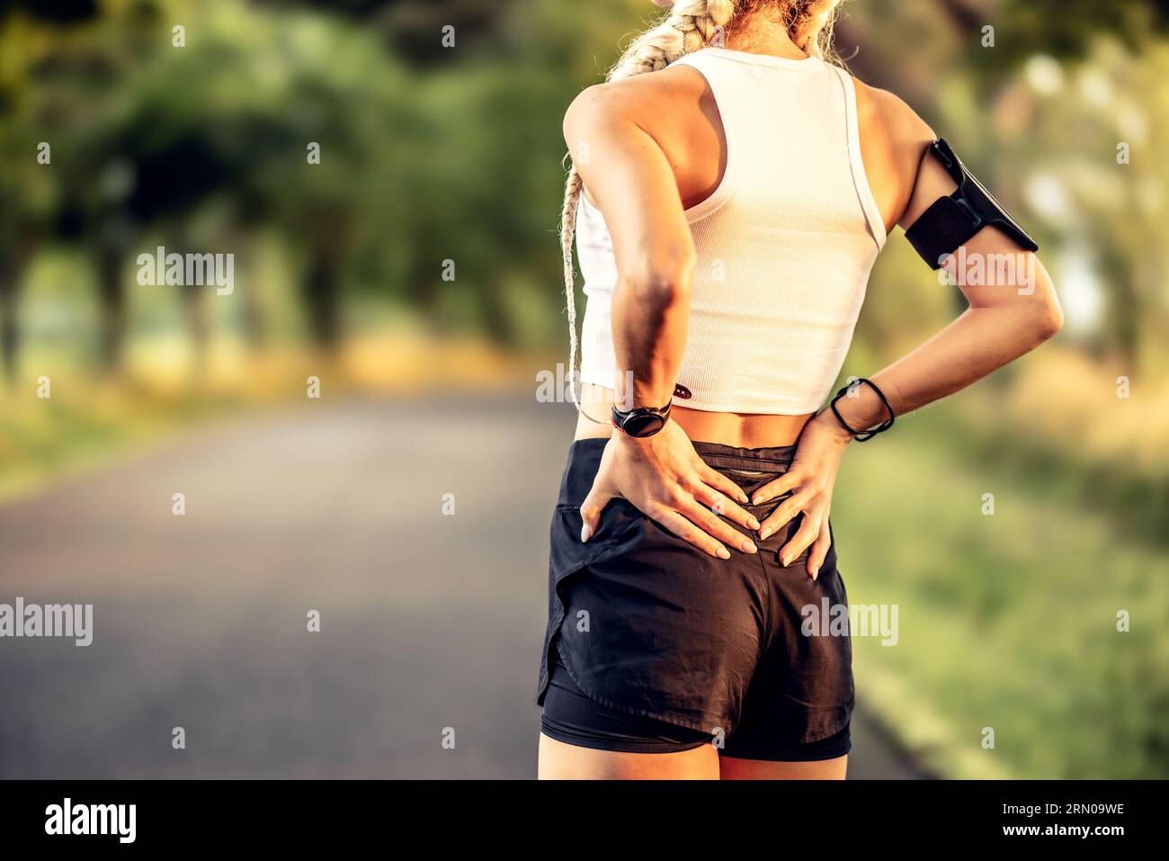 Young woman with an athletic figure and a lower back injury. Back pain during sports. Stock Photo