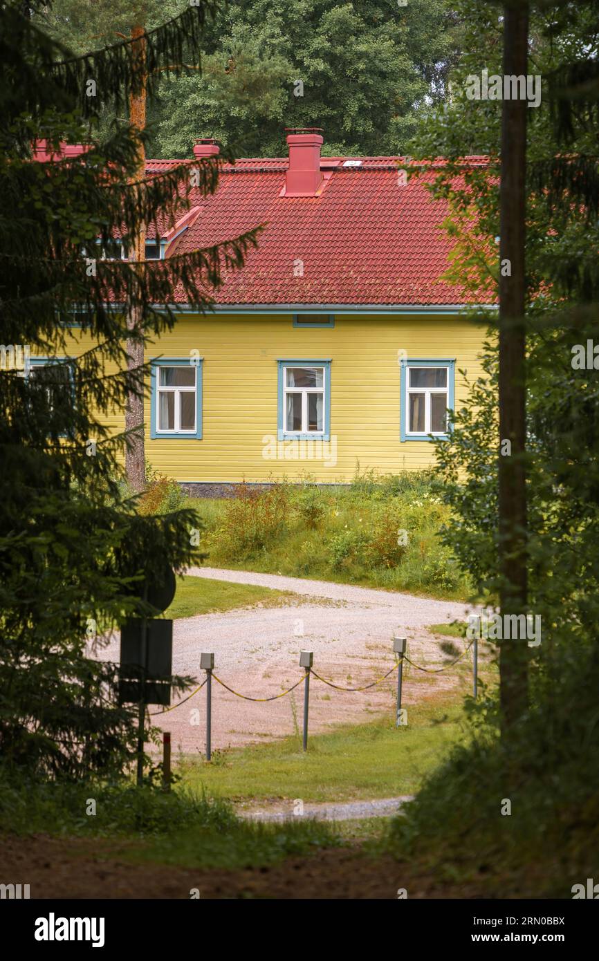 The yellow wooden house seen from the path in a forest. Stock Photo