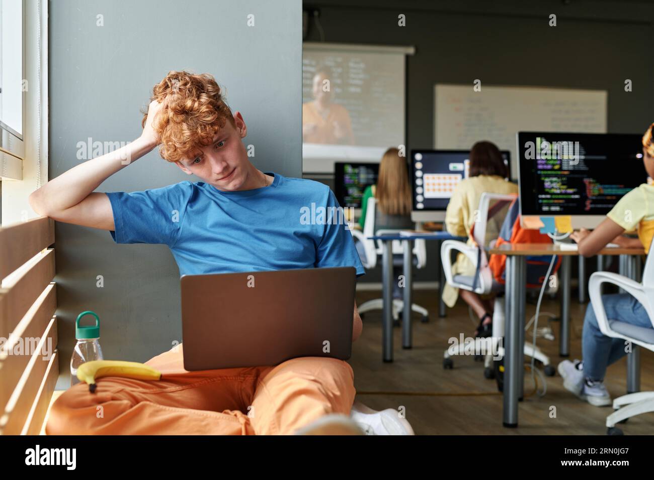 Student using laptop in the classroom while he classmates learning iT ...