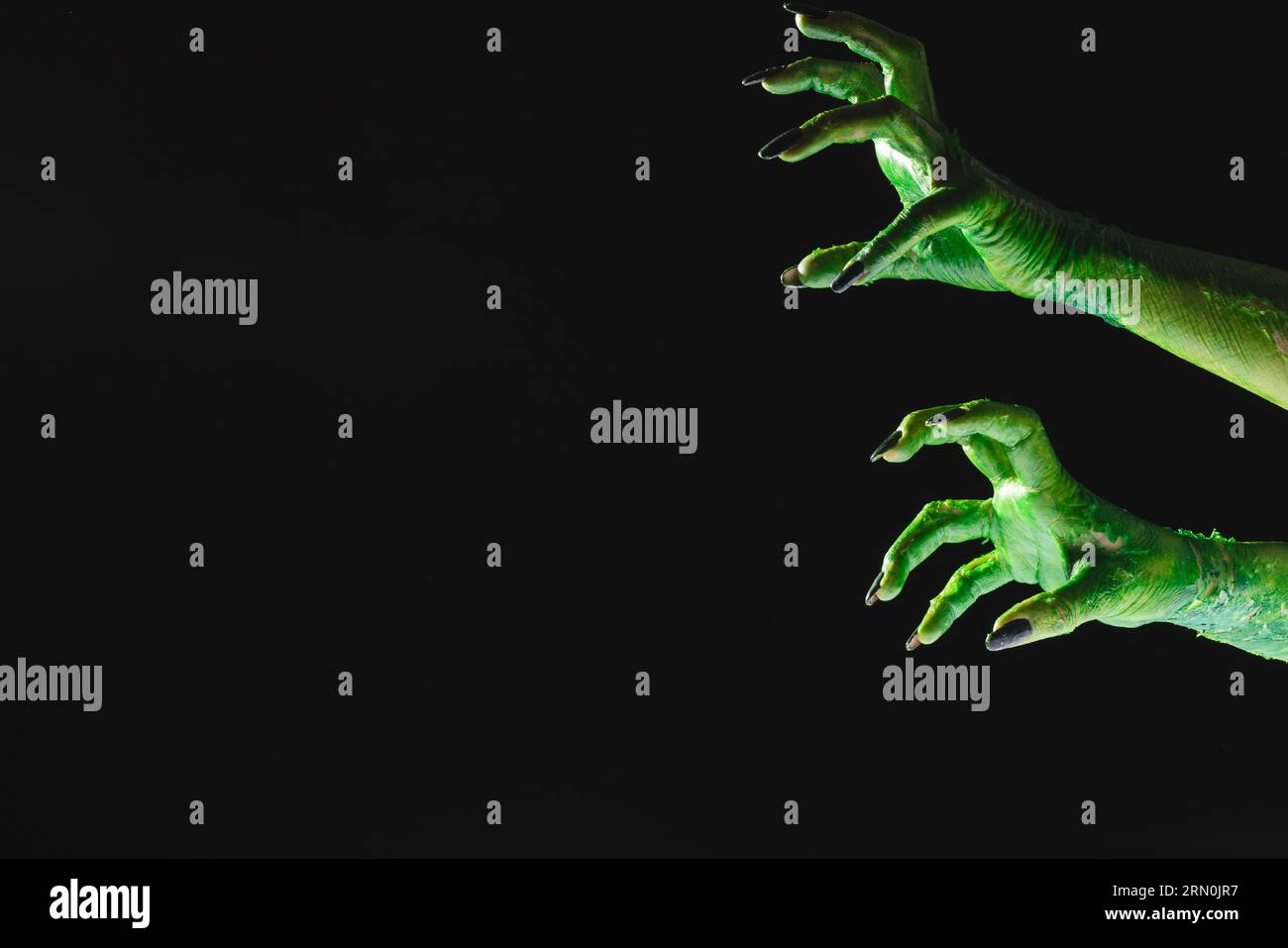 Green monster hands with black nails reaching on black background Stock