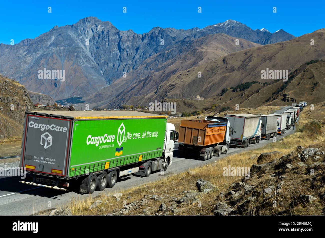 Trucks are backed up on the Georgian military road before the Zemo Larsi border checkpoint with Russia, Pansheti, Kazbegi, Georgia Stock Photo