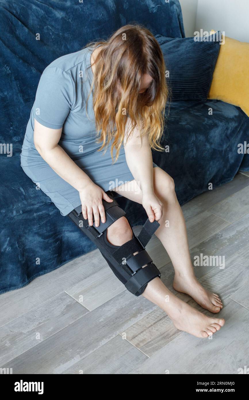 Woman wearing knee brace at home. Orthopedic Anatomic Orthosis. Braces for knee fixation