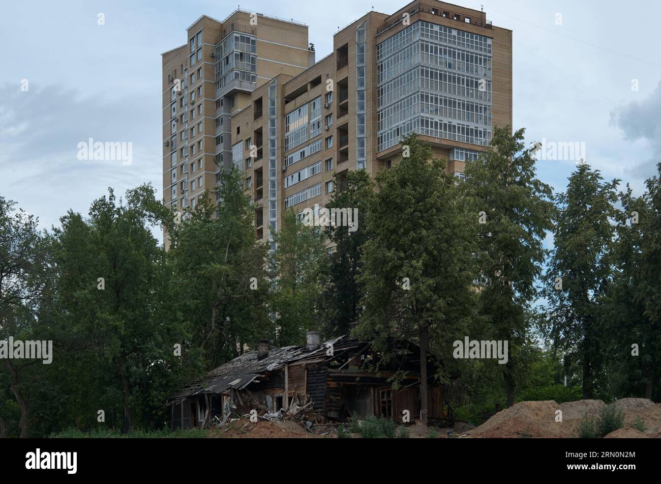 The ruins of an old house against the backdrop of a modern brick high-rise building Stock Photo