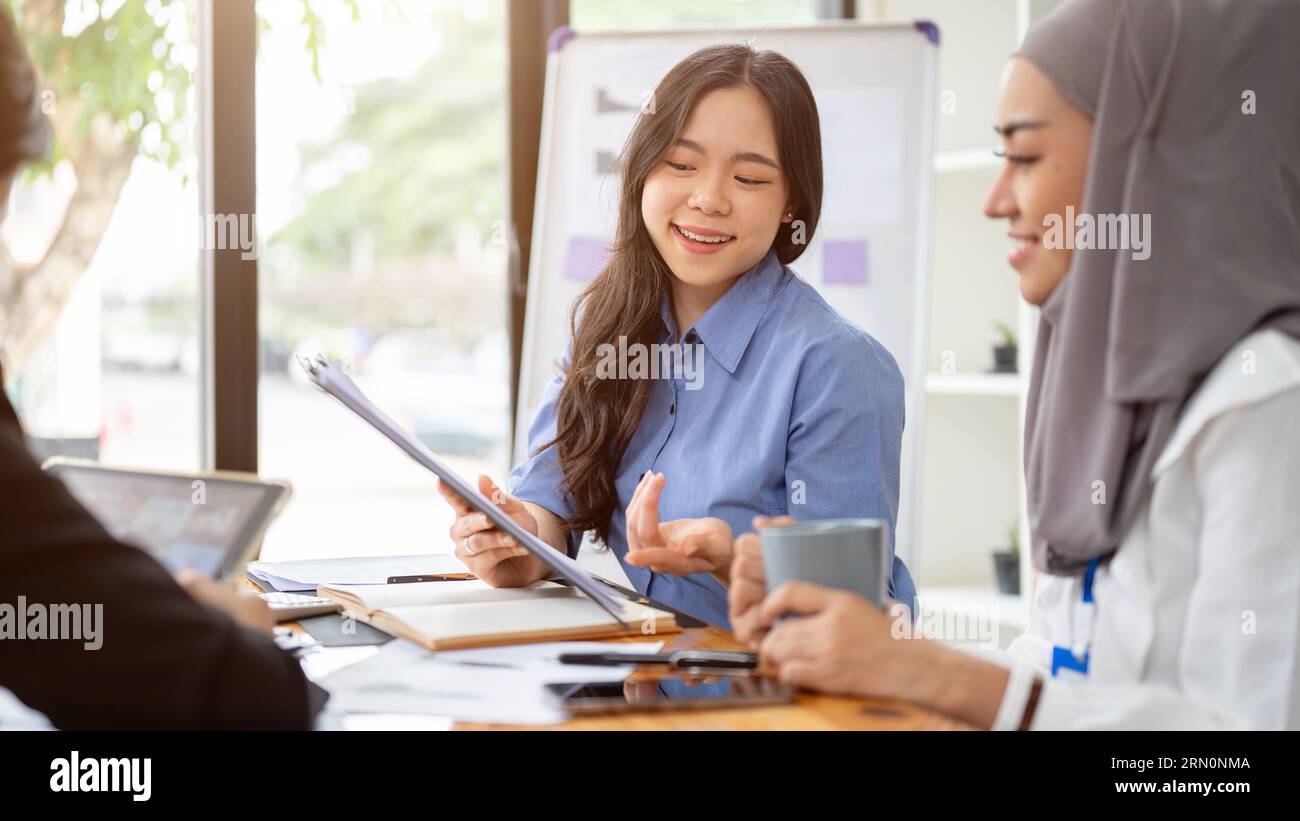 A cheerful and confident young Asian businesswoman is sharing her ideas with her team during the meeting, brainstorming and planning a project togethe Stock Photo