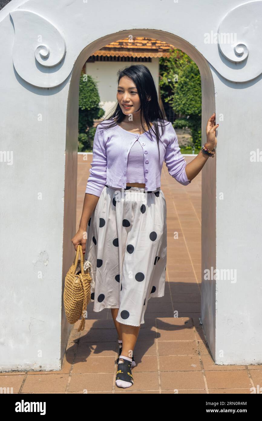A young woman walks through an entrance in a white wall Stock Photo - Alamy