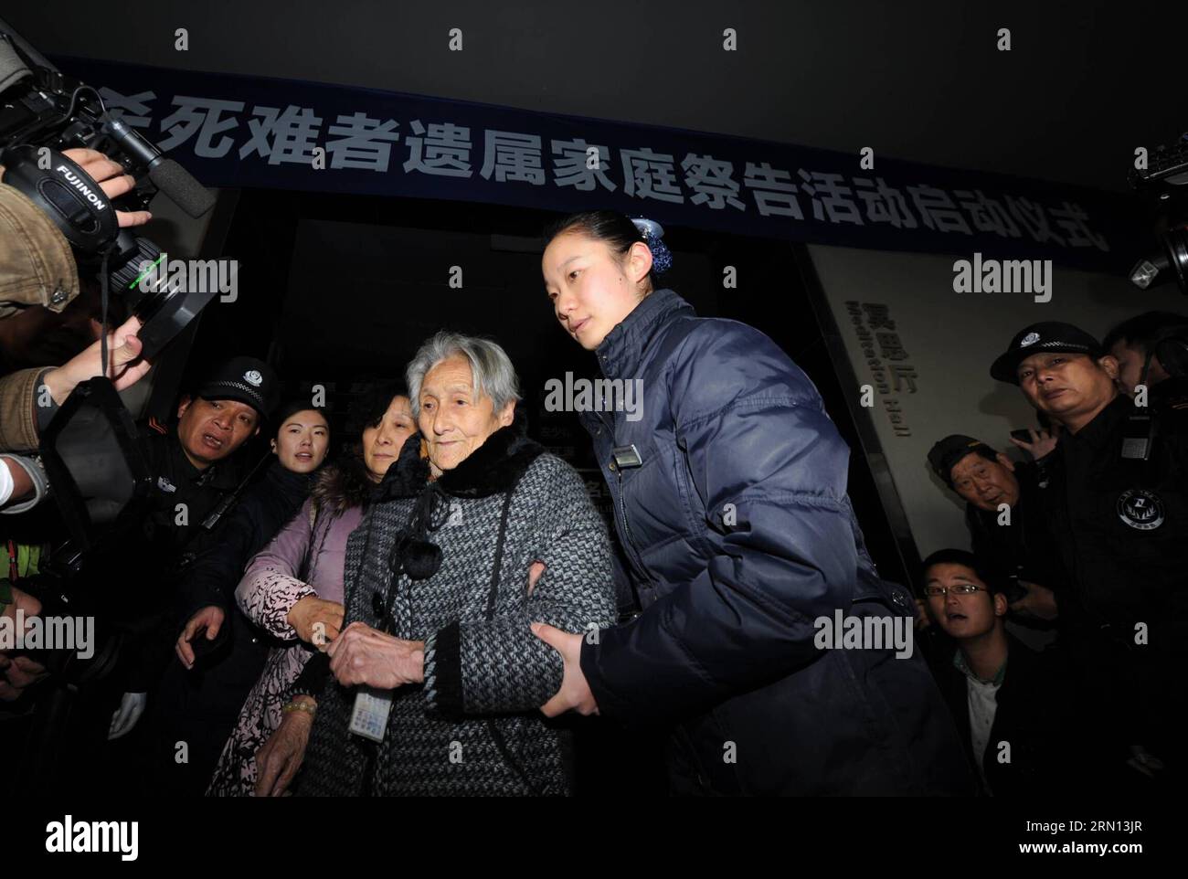 An old woman arrives to mourn her family members in front of a wall ...