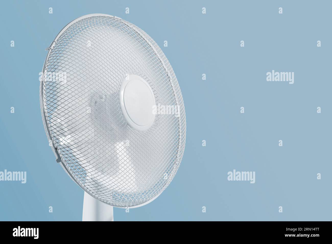 Portable electric fan working on blue background. Stock Photo